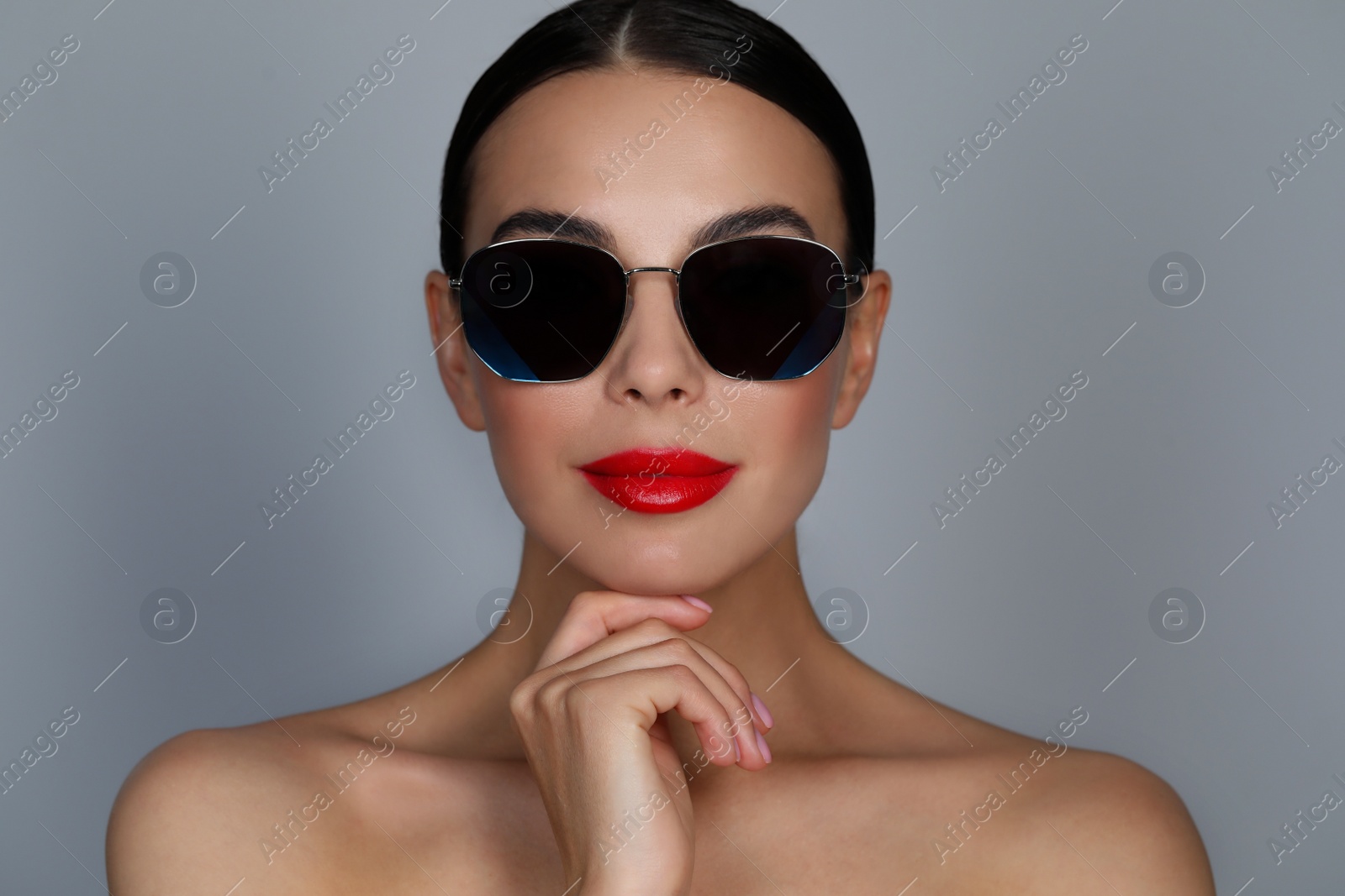 Photo of Attractive woman in fashionable sunglasses against grey background