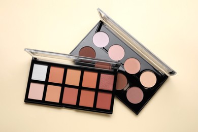 Photo of Colorful contouring palettes on beige background, top view. Professional cosmetic product