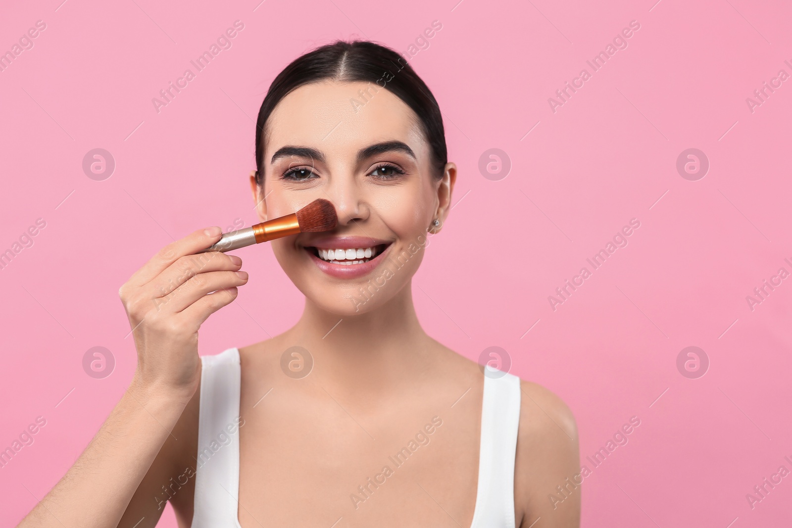 Photo of Beautiful woman applying makeup with brush on pink background. Space for text