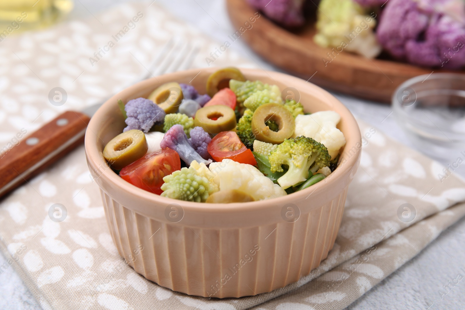 Photo of Delicious salad with cauliflower, tomato and olives on table, closeup