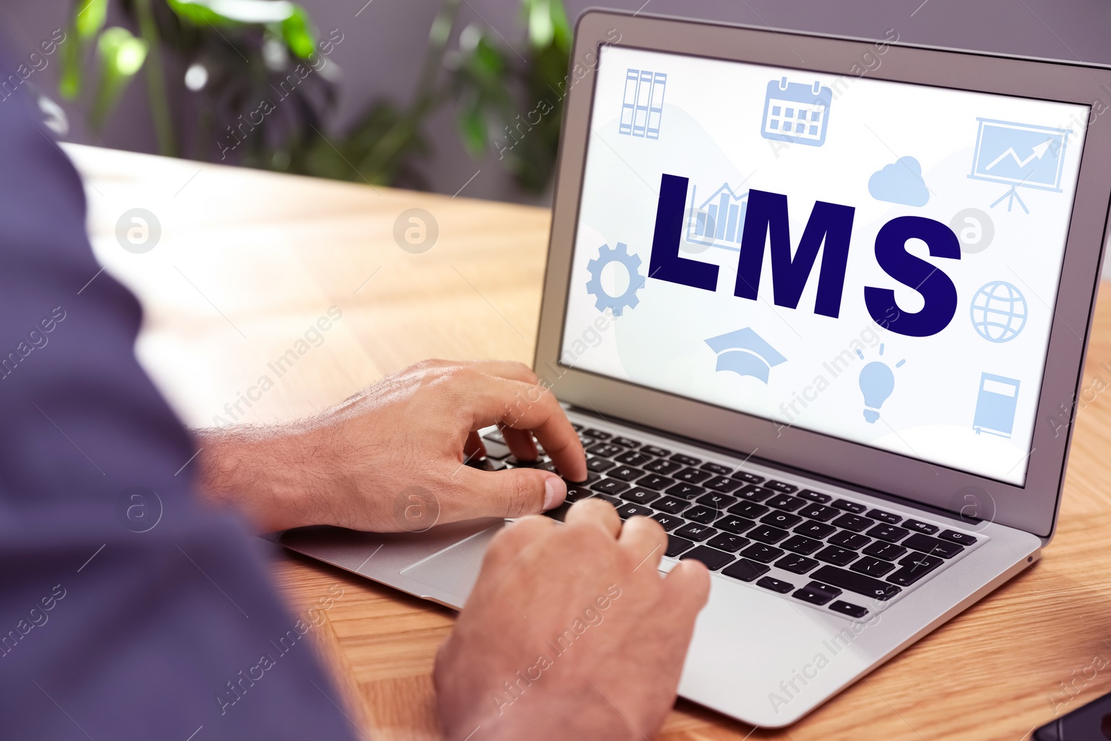 Image of Learning management system. Man using modern laptop at wooden table, closeup. Different icons and abbreviation LMS on screen