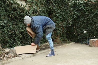 Poor homeless man with cardboard on street