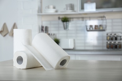 Photo of Rolls of paper towels on table in kitchen. Space for text