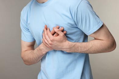 Man suffering from heart hurt on grey background, closeup