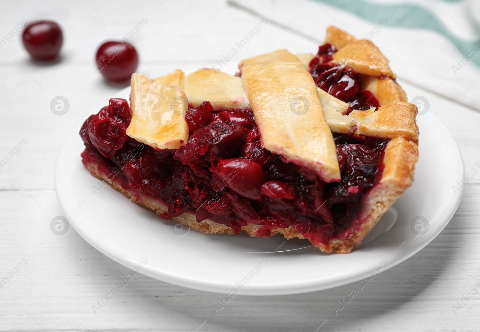 Photo of Slice of delicious fresh cherry pie on white wooden table, closeup