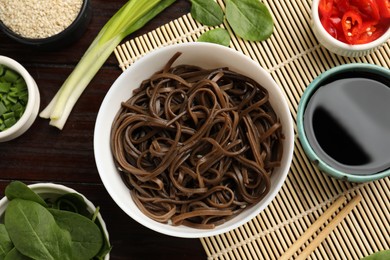 Photo of Tasty buckwheat noodles (soba) served on wooden table, flat lay