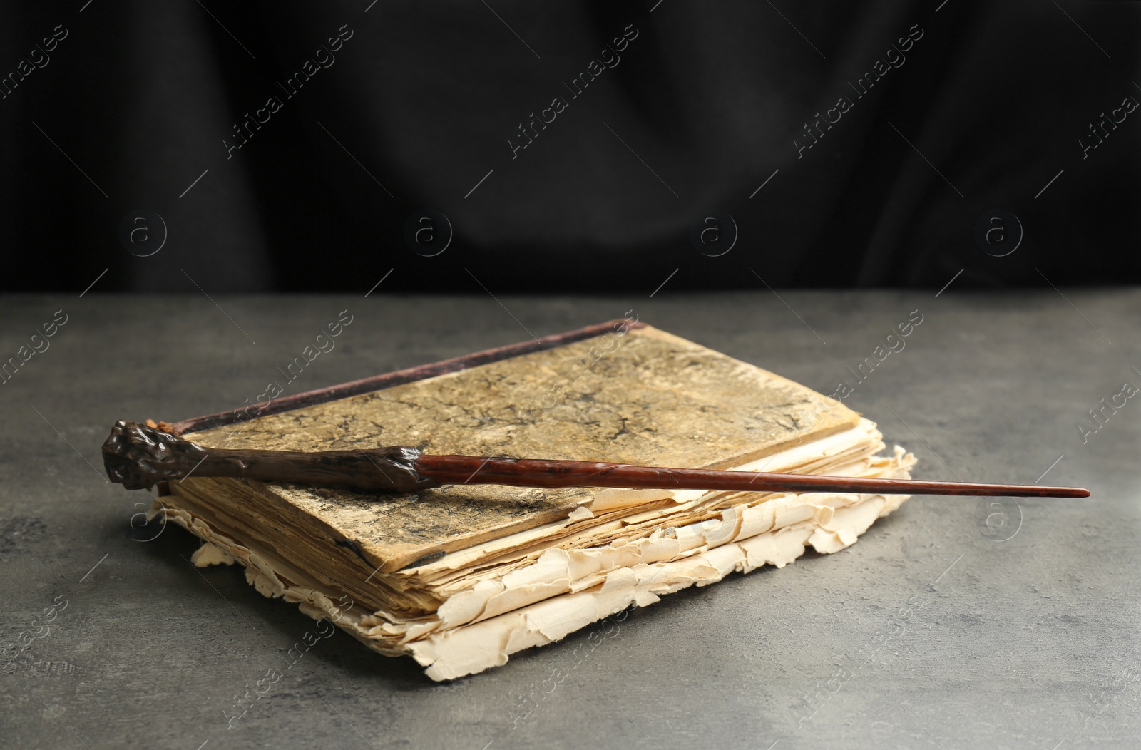 Photo of Magic wand and old book on light grey table