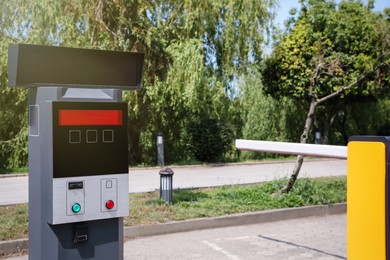 Modern road barrier and parking meter outdoors on sunny day