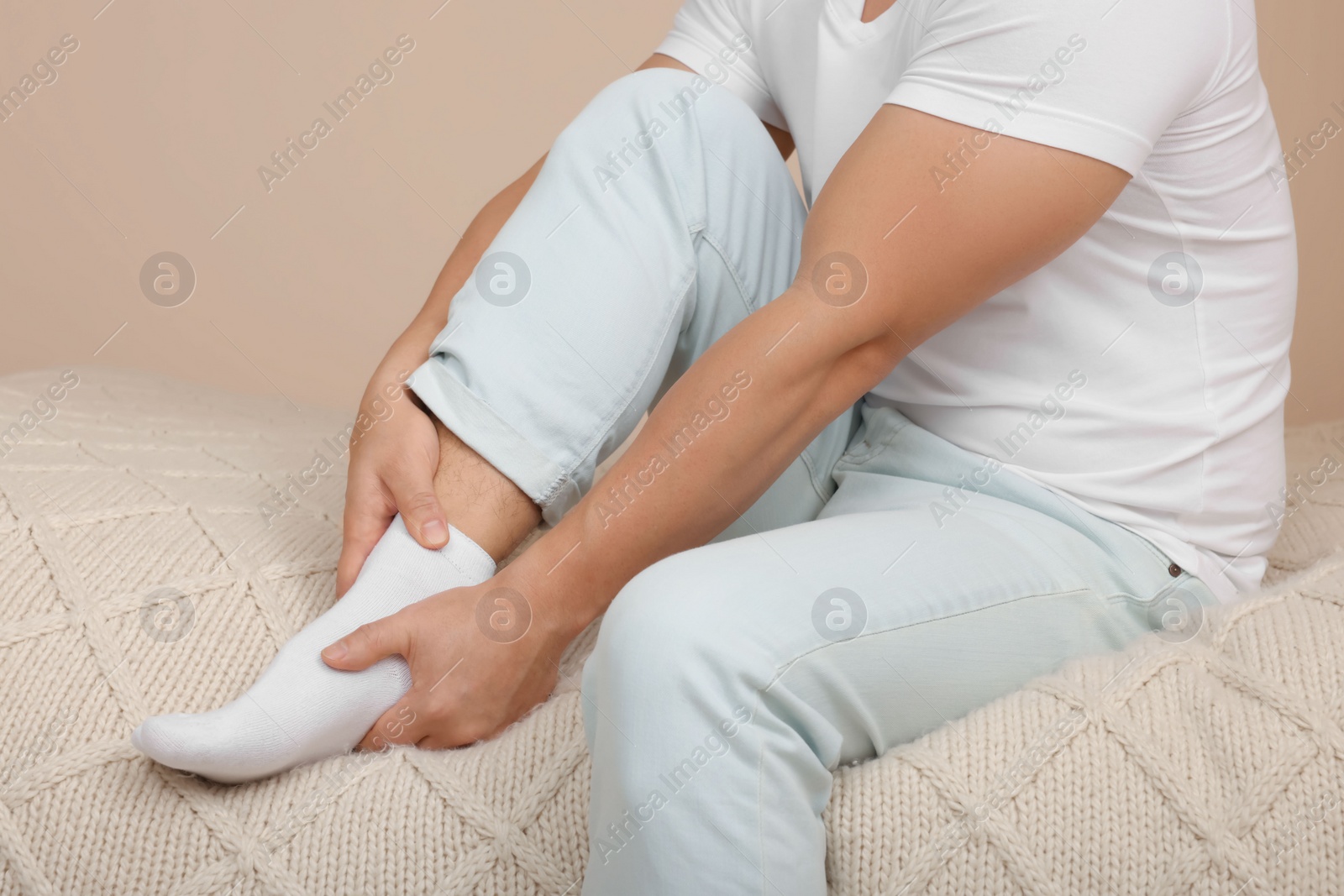 Photo of Man suffering from foot pain on bed indoors, closeup