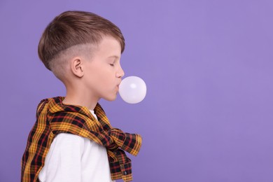 Photo of Boy blowing bubble gum on purple background, space for text