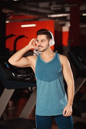 Young man listening to music with headphones at gym