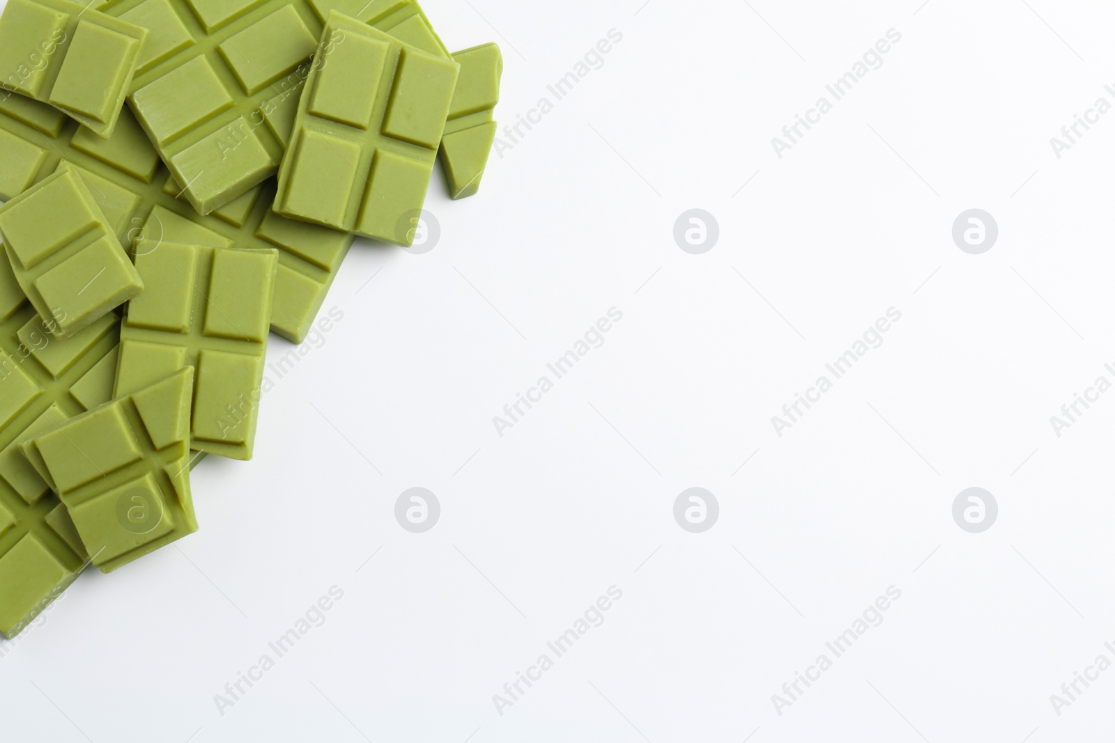 Photo of Pieces of tasty matcha chocolate bars on white background, top view. Space for text