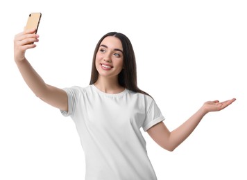 Smiling young woman taking selfie with smartphone on white background