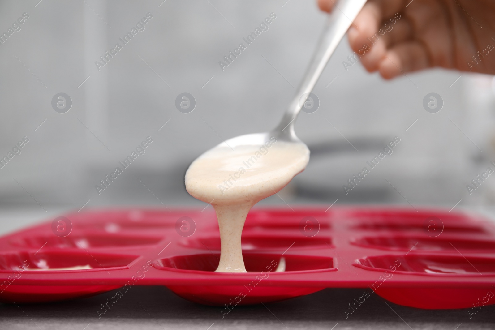 Photo of Woman pouring batter into baking mold at table, closeup. Madeleine cookies