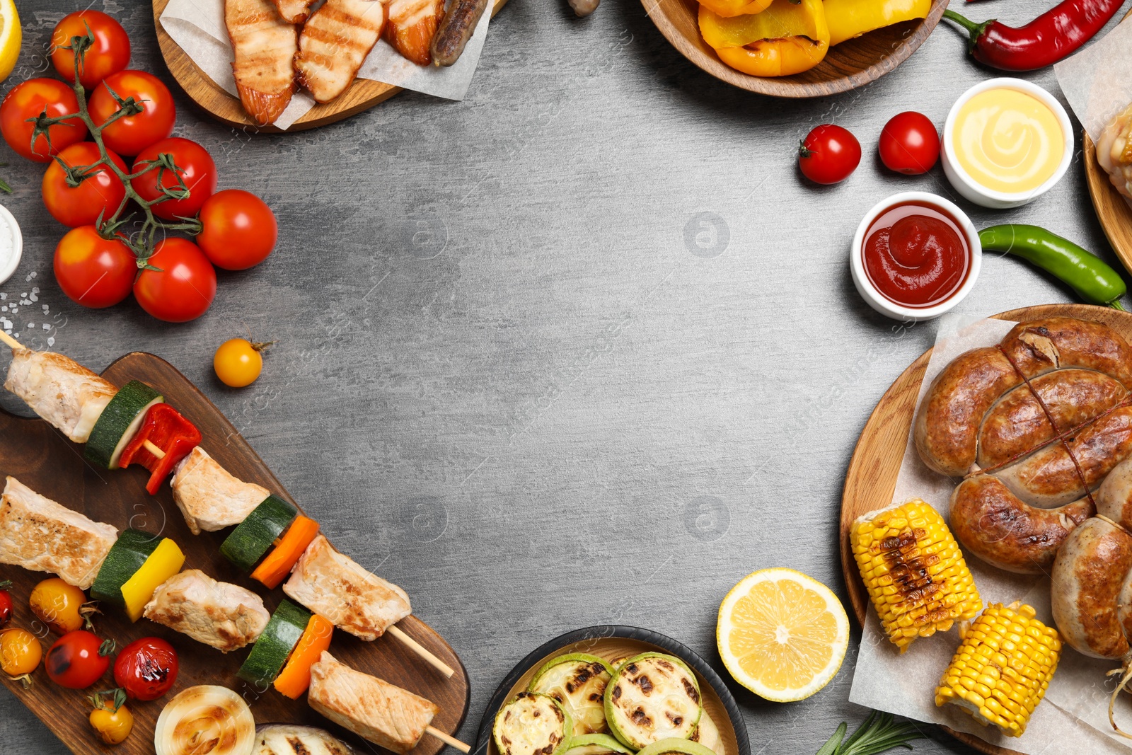 Photo of Frame of barbecued meat and vegetables on grey table, flat lay. Space for text