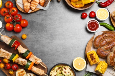 Frame of barbecued meat and vegetables on grey table, flat lay. Space for text