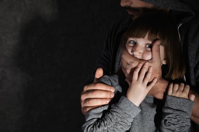 Photo of Adult man covering scared little girl's mouth, space for text. Child in danger