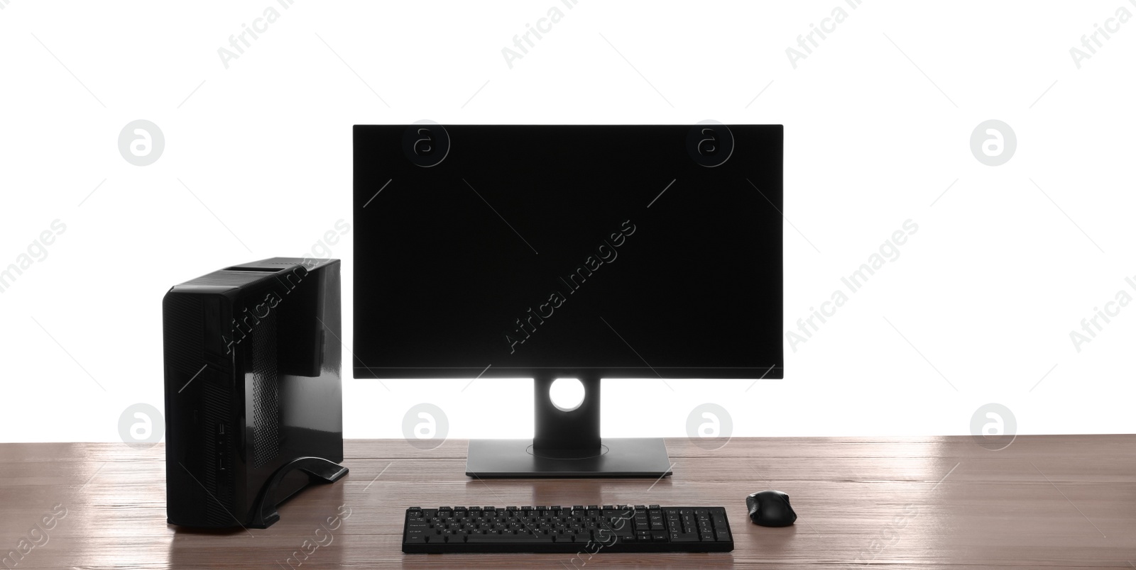 Photo of Modern computer with blank monitor screen and peripherals on wooden table against white background