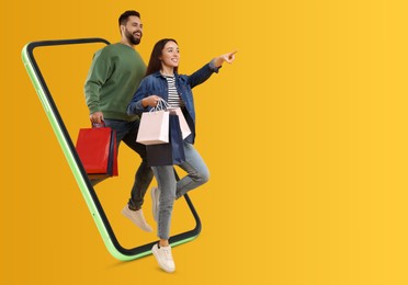 Image of Online shopping. Happy couple with paper bags walking out from smartphone on orange background, space for text