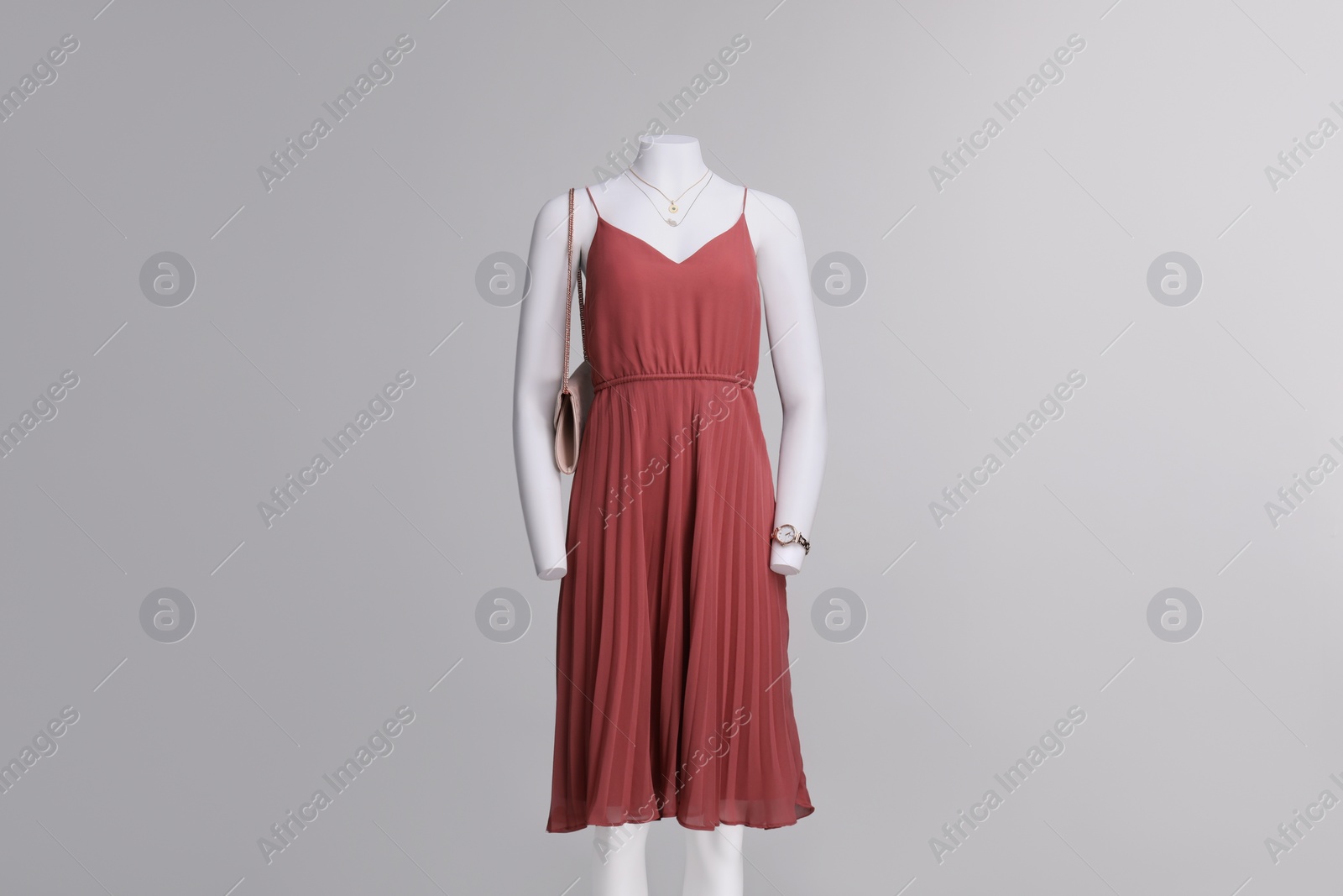 Photo of Female mannequin with necklace and bag dressed in stylish red dress on grey background