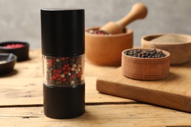 Photo of Different peppercorns on wooden table, closeup. Space for text