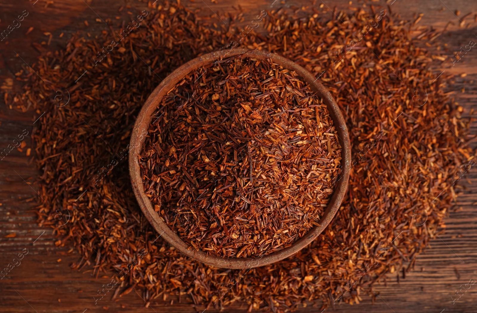 Photo of Dry rooibos leaves on wooden table, flat lay