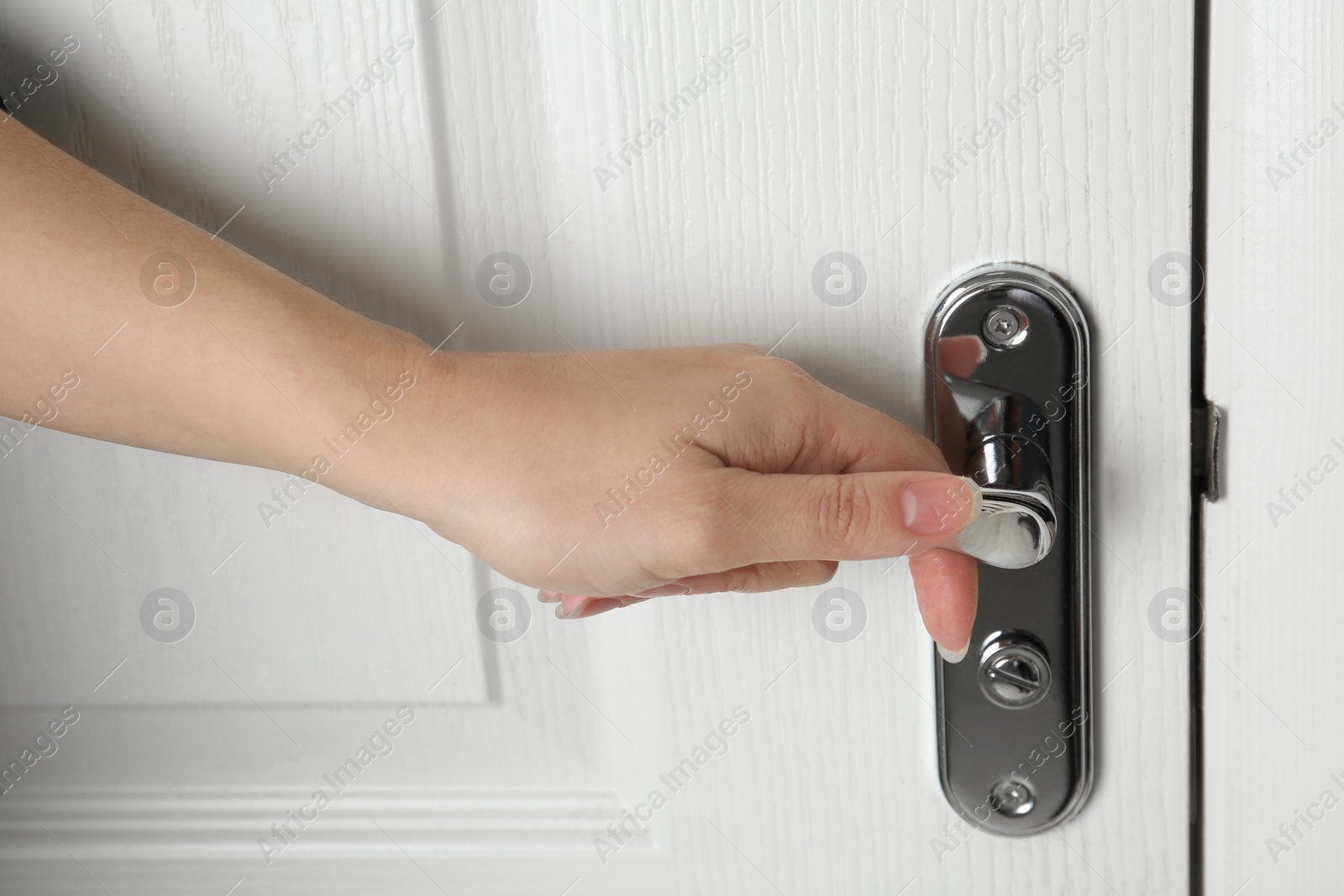 Photo of Woman opening white wooden door indoors, closeup