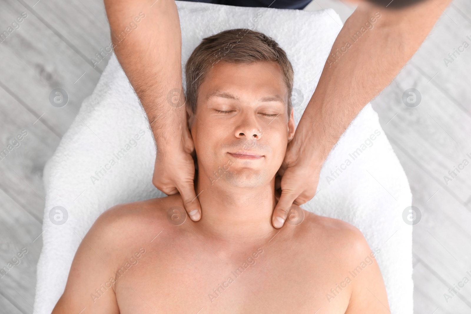 Photo of Relaxed man receiving head massage in wellness center, top view