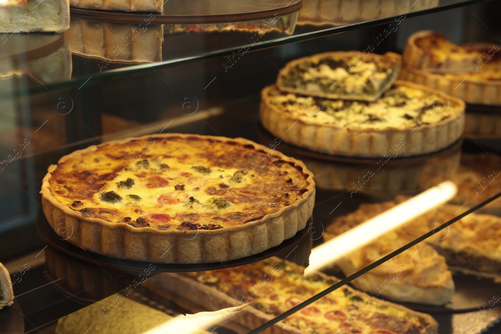 Photo of Different delicious quiches on counter in bakery shop, closeup