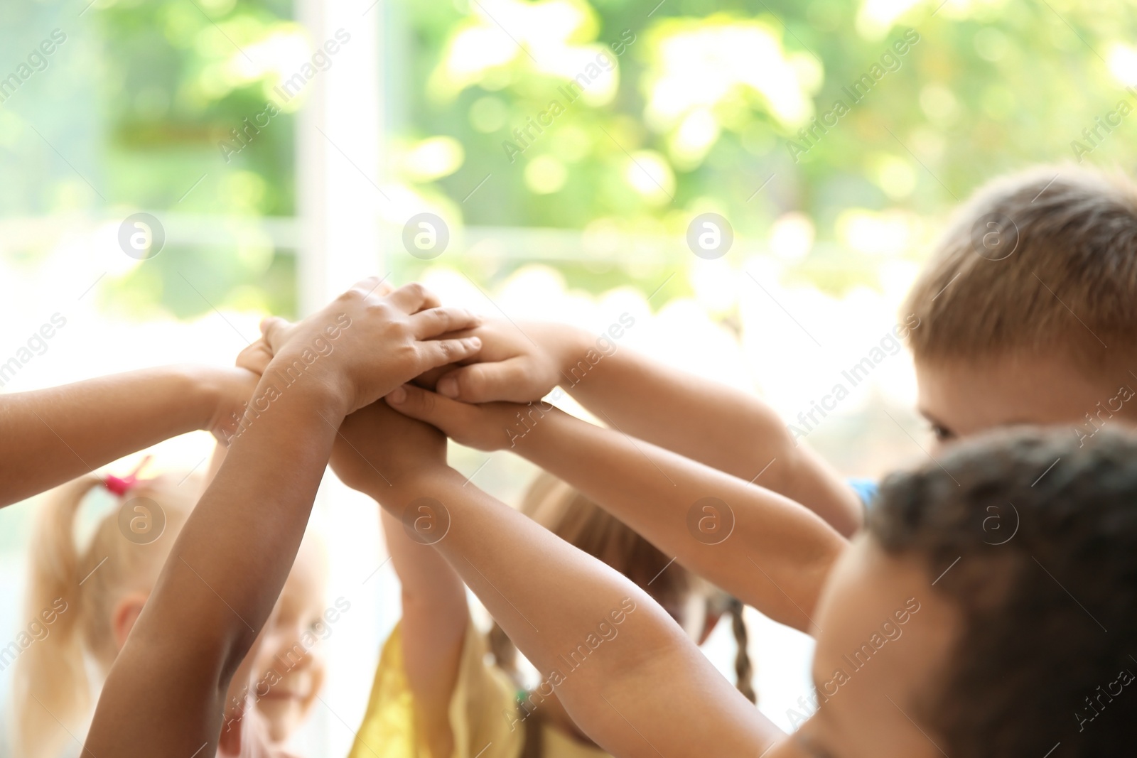 Photo of Little children putting their hands together on blurred background. Unity concept