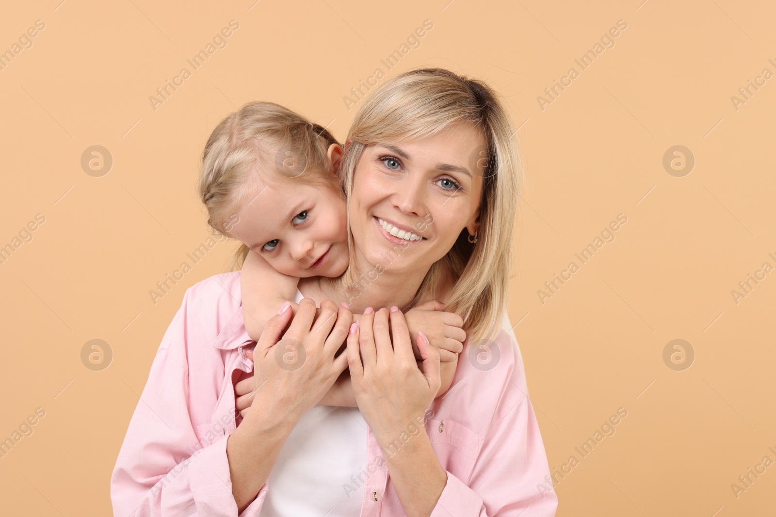 Photo of Daughter hugging her happy mother on beige background