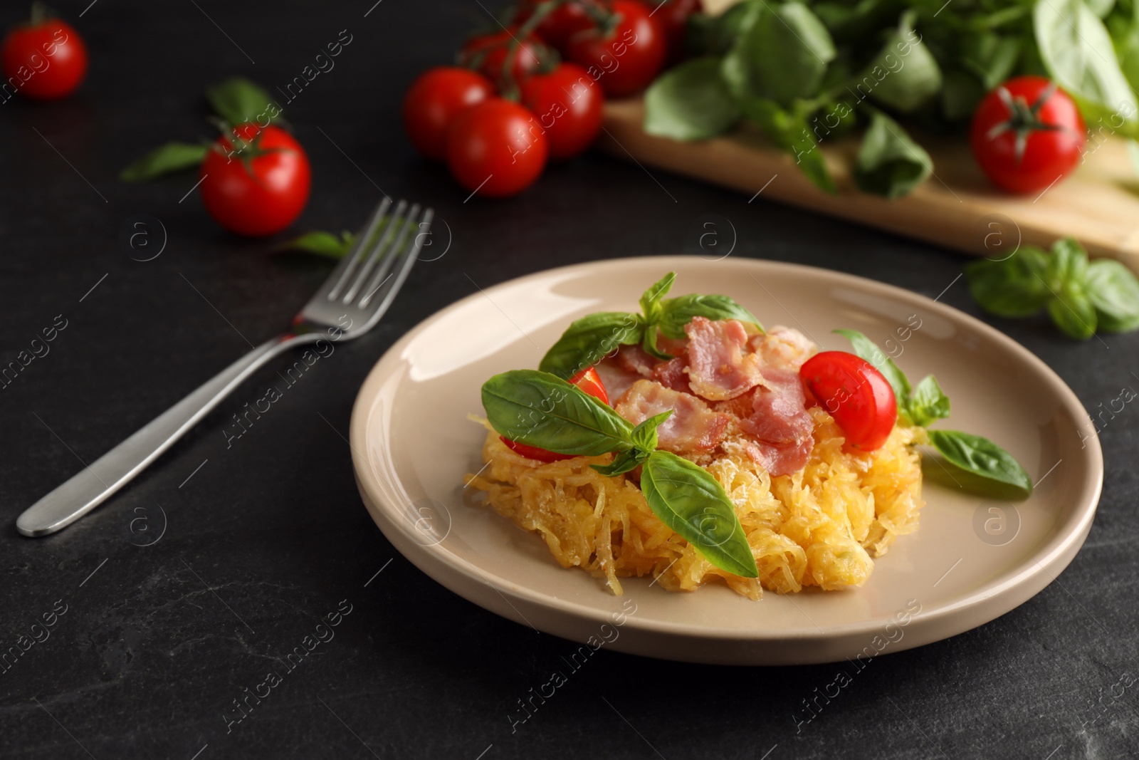 Photo of Tasty spaghetti squash with bacon and basil served on black table