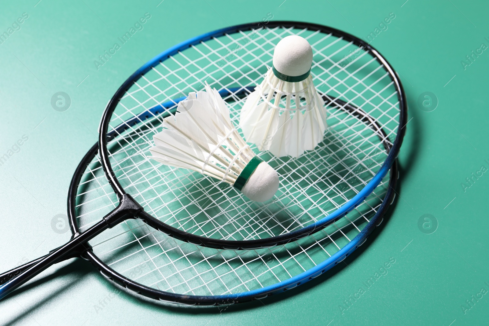 Photo of Feather badminton shuttlecocks and rackets on green background, closeup