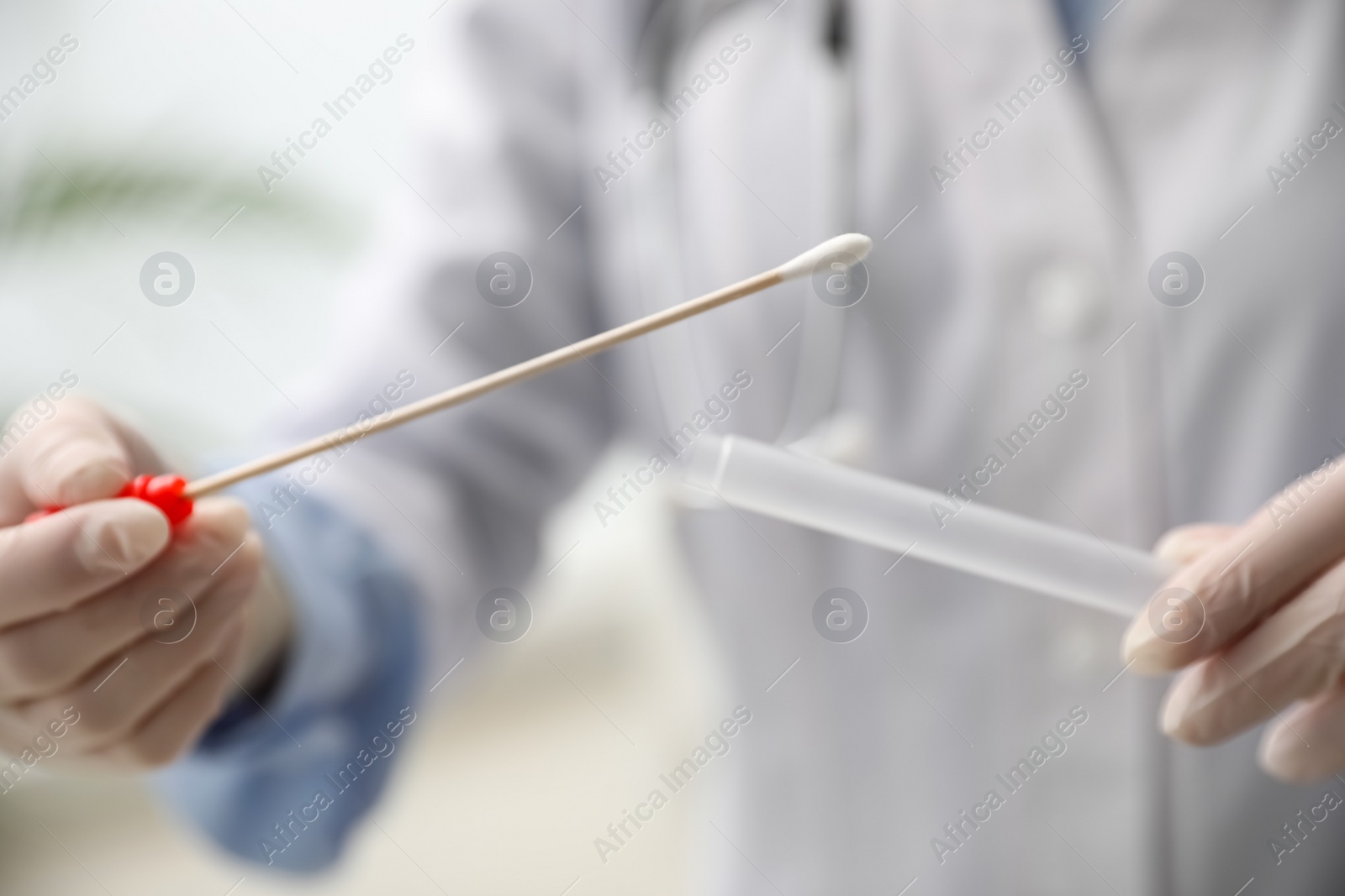 Photo of Doctor holding buccal cotton swab and tube for DNA test in clinic, closeup