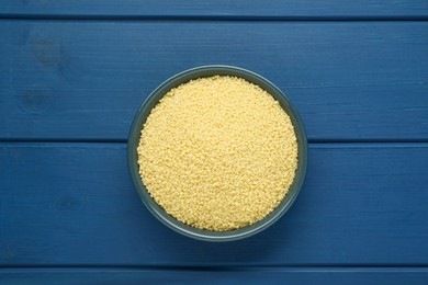 Photo of Bowl of raw couscous on blue wooden table, top view