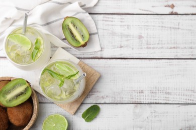 Photo of Refreshing drink with kiwi and ingredients on white wooden table, flat lay. Space for text