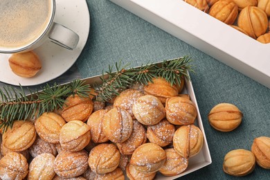 Box with delicious nut shaped cookies and coffee on table, flat lay