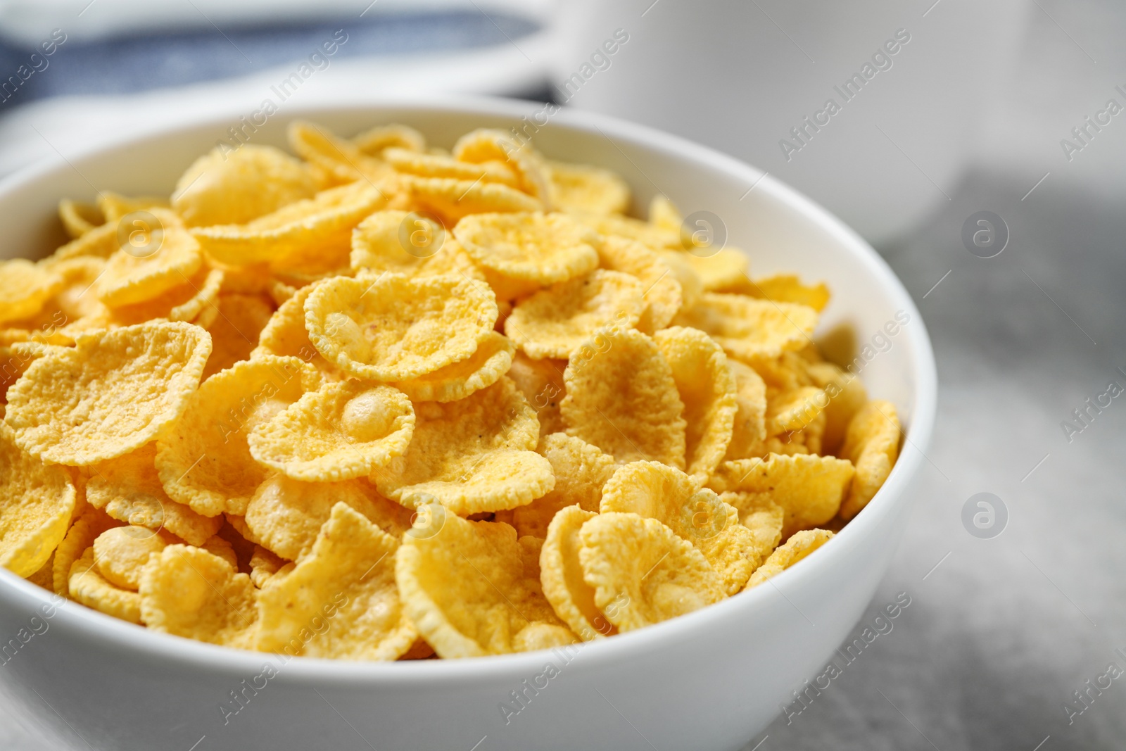 Photo of Tasty corn flakes on light grey table, closeup