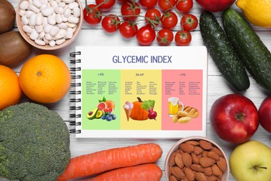 Image of Glycemic index. Information about grouping of products under their GI in notebook, fruits, vegetables, almonds and beans on white wooden table, flat lay