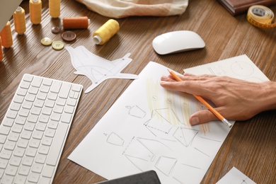 Male fashion designer working at wooden table, closeup