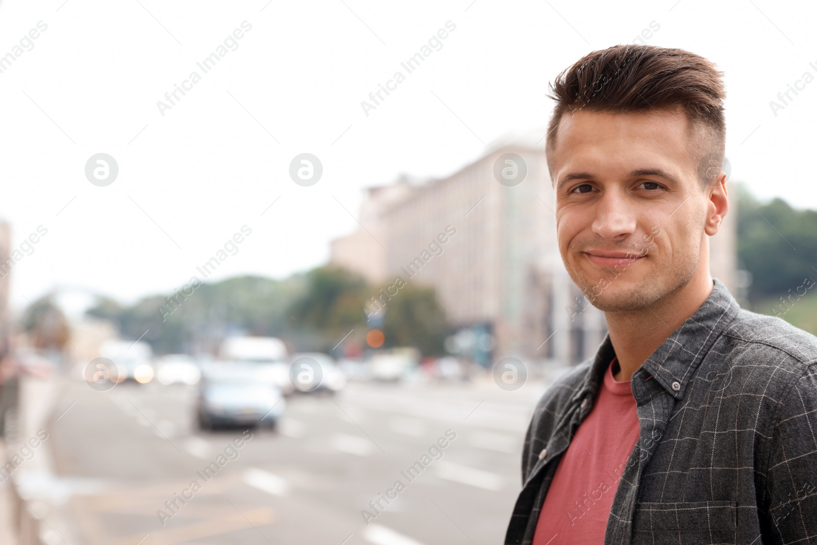 Photo of Portrait of handsome young man on city street. Space for text