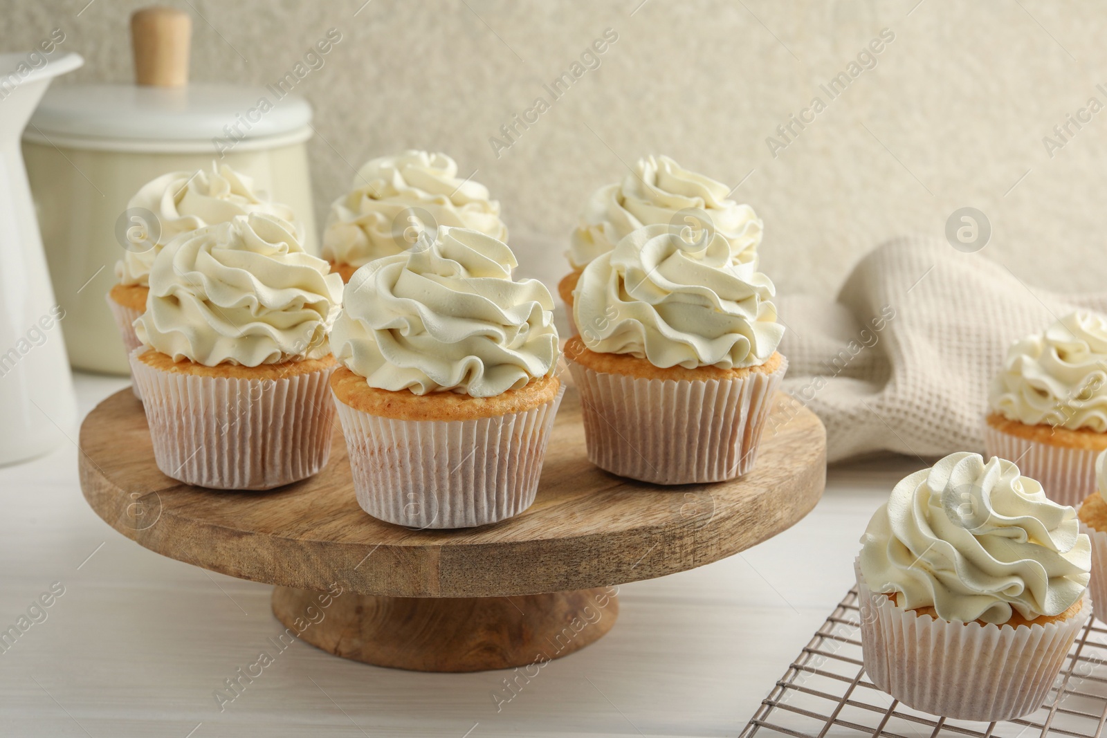 Photo of Tasty vanilla cupcakes with cream on white wooden table