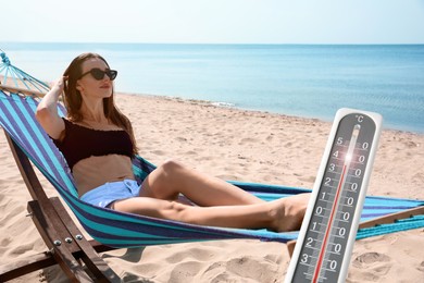Weather thermometer and young woman relaxing in hammock on beach on background. Heat stroke warning