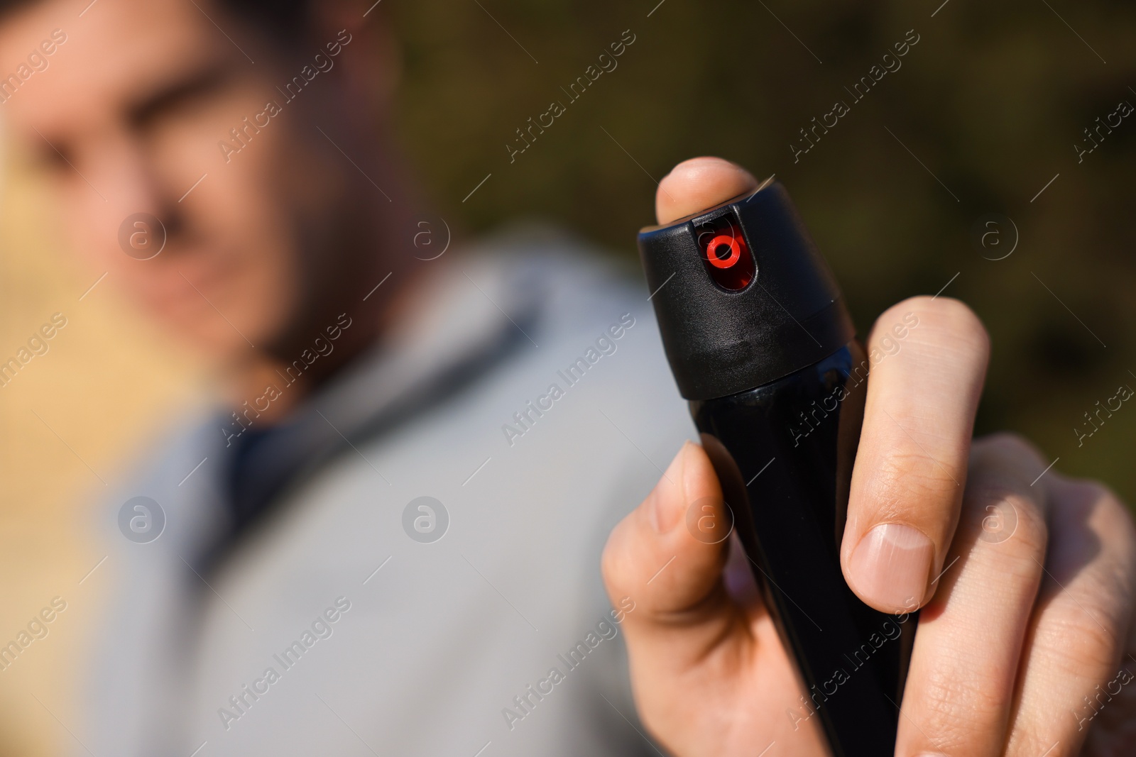 Photo of Man using pepper spray outdoors, focus on hand. Space for text