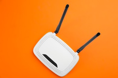 Photo of Modern Wi-Fi router on orange background, top view