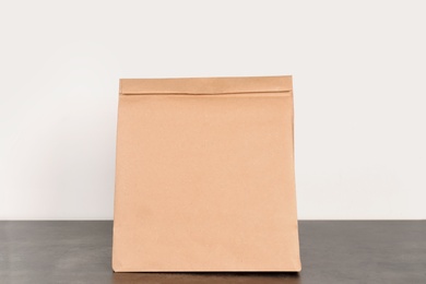 Paper bag on table against white wall. Mockup for design