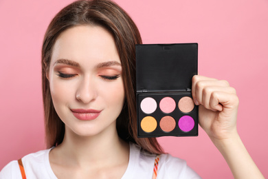 Beauty blogger with eyeshadow palette on pink background