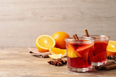 Photo of Aromatic punch drink and ingredients on wooden table, space for text