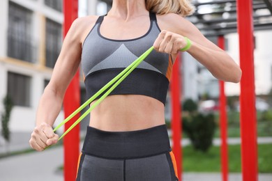Photo of Fit woman doing exercise with fitness elastic band at outdoor gym, closeup