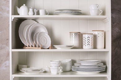 Stylish storage stand with different ceramic dishware at home